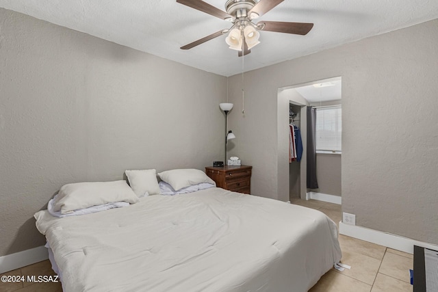 bedroom featuring light tile patterned flooring, ceiling fan, a spacious closet, and a closet