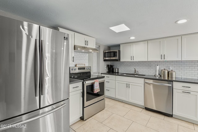 kitchen featuring light tile patterned flooring, appliances with stainless steel finishes, tasteful backsplash, sink, and white cabinets