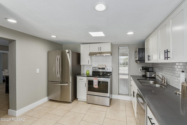 kitchen with sink, light tile patterned floors, appliances with stainless steel finishes, white cabinetry, and tasteful backsplash