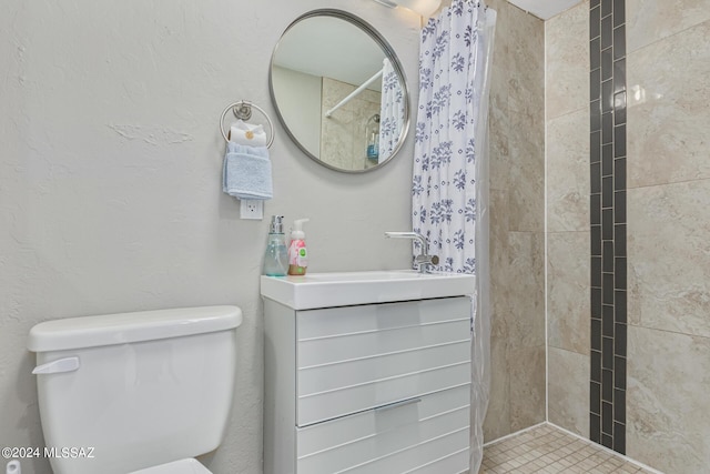 bathroom with vanity, a tile shower, and toilet