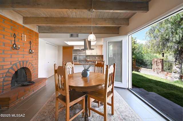 dining room featuring beam ceiling, tile patterned floors, and a fireplace