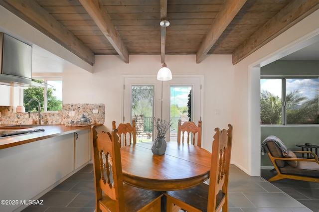 dining area with beamed ceiling, dark tile patterned floors, and wood ceiling