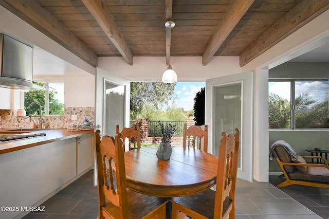 dining room featuring beam ceiling, dark tile patterned flooring, and wood ceiling