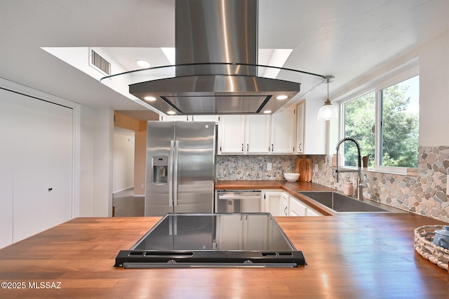 kitchen featuring island range hood, butcher block countertops, sink, hanging light fixtures, and stainless steel appliances