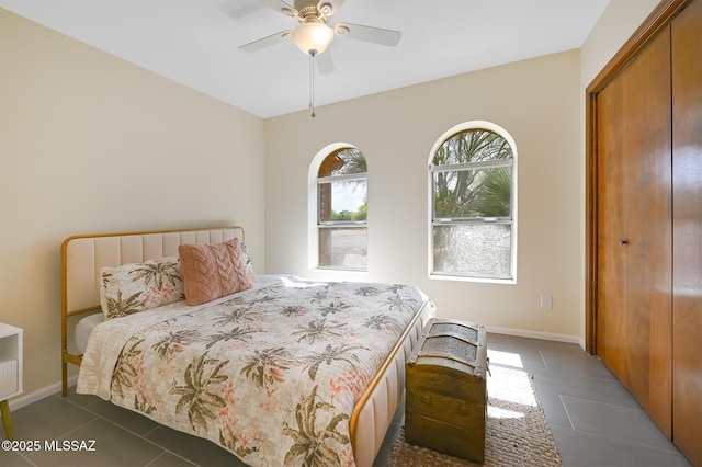 bedroom featuring dark tile patterned floors, ceiling fan, and a closet