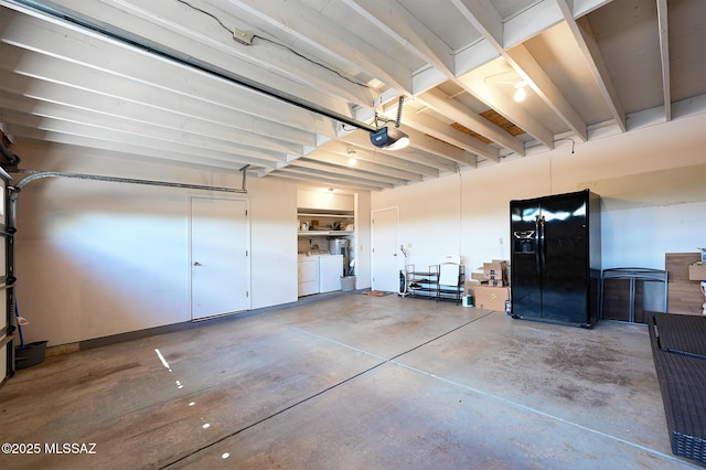 garage featuring black fridge, a garage door opener, and washer and dryer