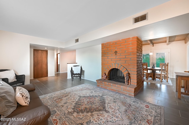 living room featuring beam ceiling, a brick fireplace, and dark tile patterned floors