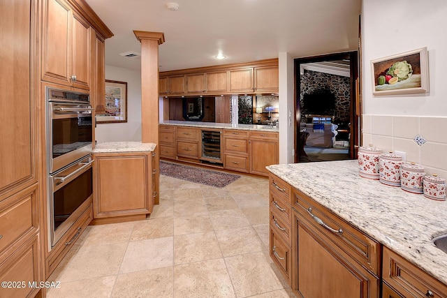 kitchen featuring beverage cooler, light stone countertops, and backsplash