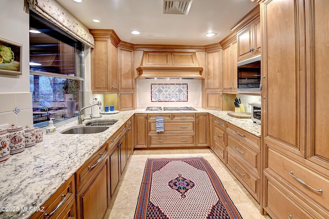 kitchen with premium range hood, appliances with stainless steel finishes, tasteful backsplash, sink, and light stone countertops