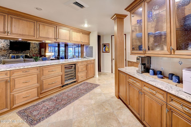 kitchen with wine cooler, decorative backsplash, and light stone countertops