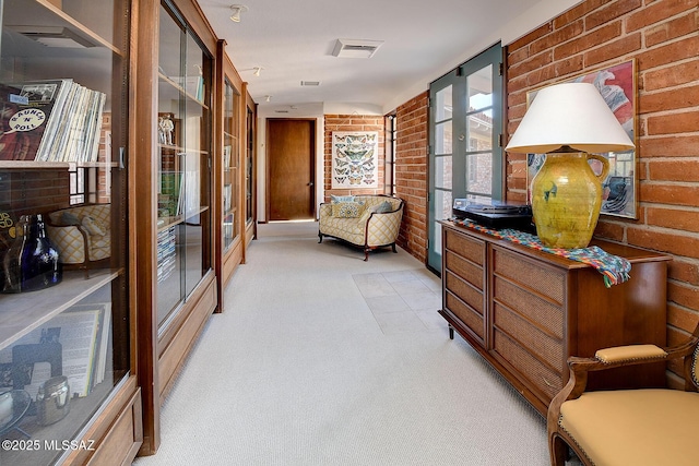 sitting room with brick wall, light colored carpet, and french doors