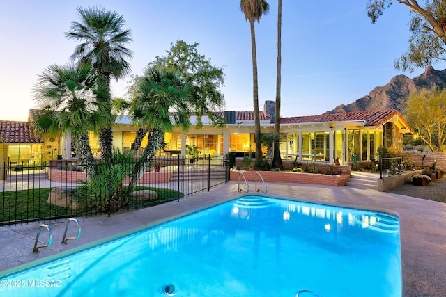 pool at dusk featuring a mountain view and a patio area