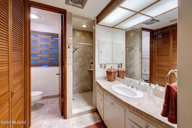 bathroom with vanity, tile patterned floors, toilet, and tiled shower