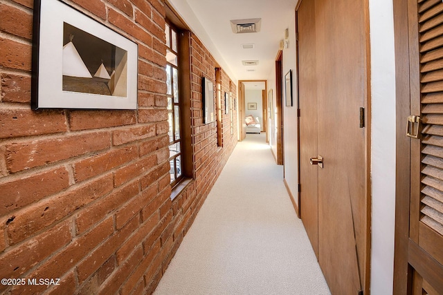 corridor with brick wall and light colored carpet