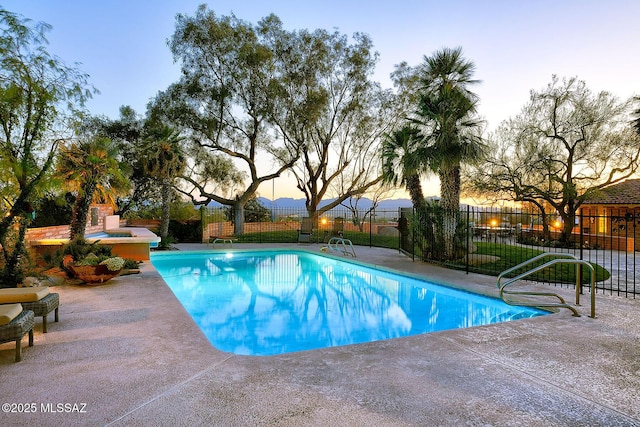 pool at dusk with a patio area