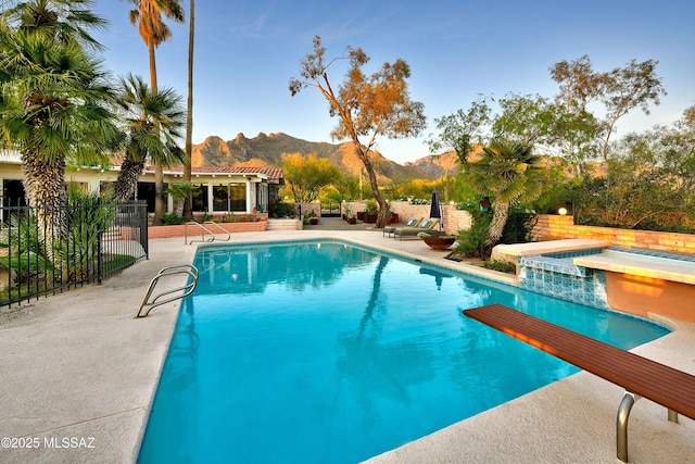 view of swimming pool with a mountain view, a jacuzzi, a patio area, and a diving board