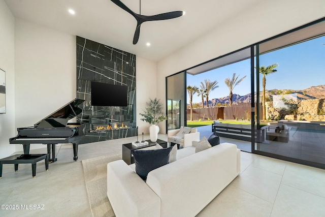 living room with ceiling fan, a premium fireplace, and light tile patterned floors