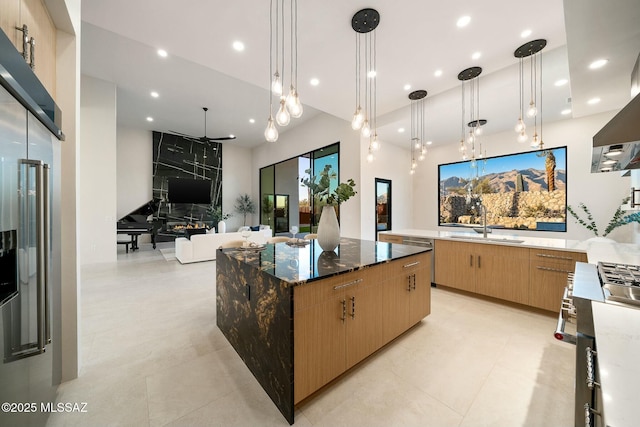 kitchen with a large island, decorative light fixtures, stainless steel range with gas stovetop, and dark stone countertops