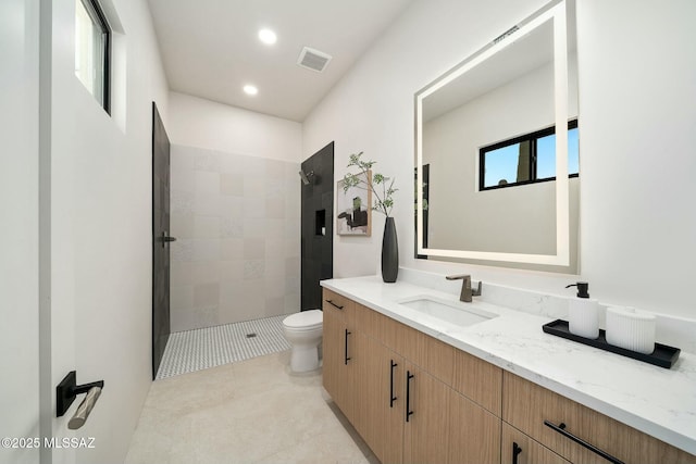 bathroom with tile patterned floors, vanity, toilet, and a tile shower