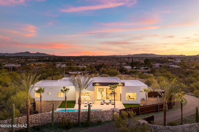 back house at dusk with a mountain view and a patio