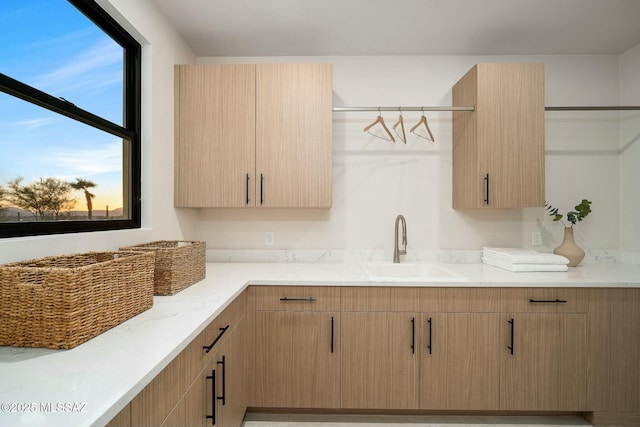 kitchen with sink, light stone countertops, and light brown cabinets