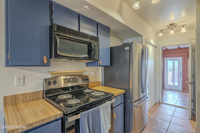 kitchen featuring appliances with stainless steel finishes, wood counters, blue cabinets, rail lighting, and light tile patterned floors