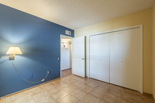 unfurnished bedroom featuring tile patterned flooring, a closet, and a textured ceiling