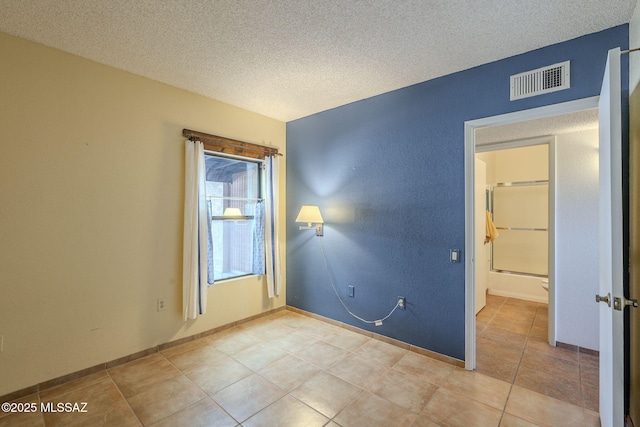 tiled spare room with a textured ceiling