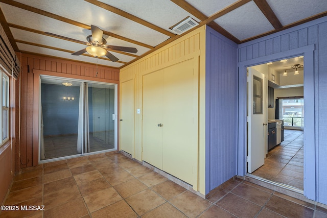 unfurnished sunroom with ceiling fan and beam ceiling