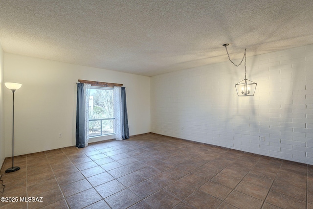 tiled spare room featuring a textured ceiling and brick wall