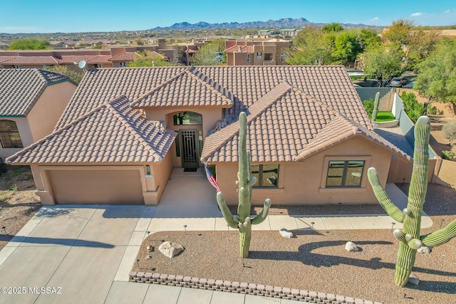 view of front facade featuring a mountain view, a garage, a tiled roof, driveway, and stucco siding