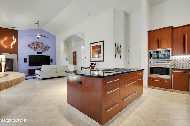 kitchen with appliances with stainless steel finishes, a kitchen island, high vaulted ceiling, and decorative backsplash