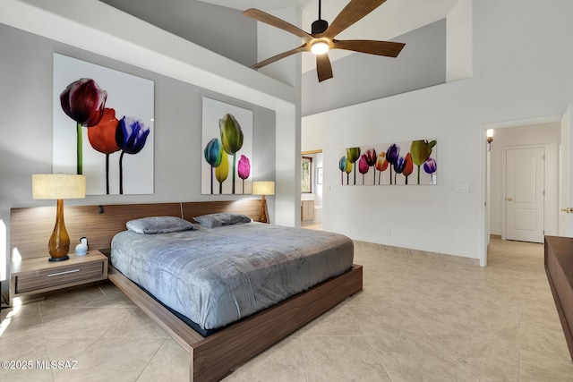 bedroom featuring a ceiling fan, ensuite bath, and a high ceiling