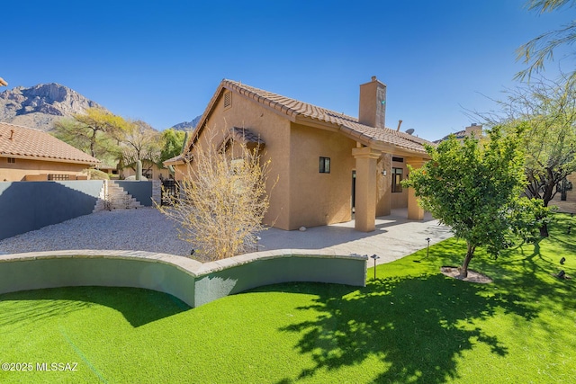 back of property featuring fence, a tile roof, stucco siding, a chimney, and a patio area