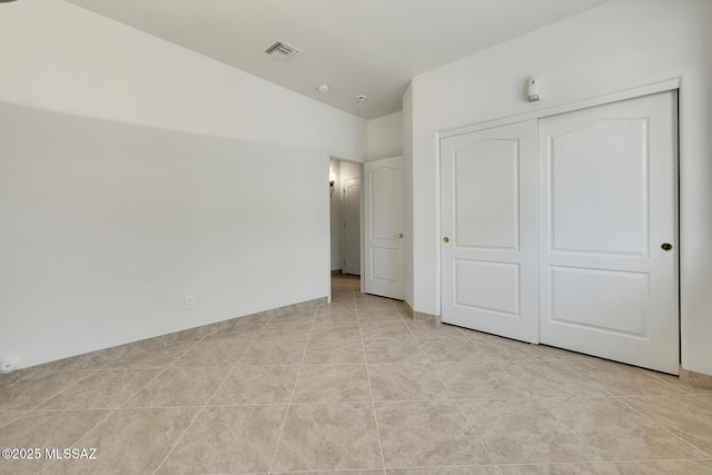 unfurnished bedroom featuring light tile patterned floors, baseboards, visible vents, and a closet