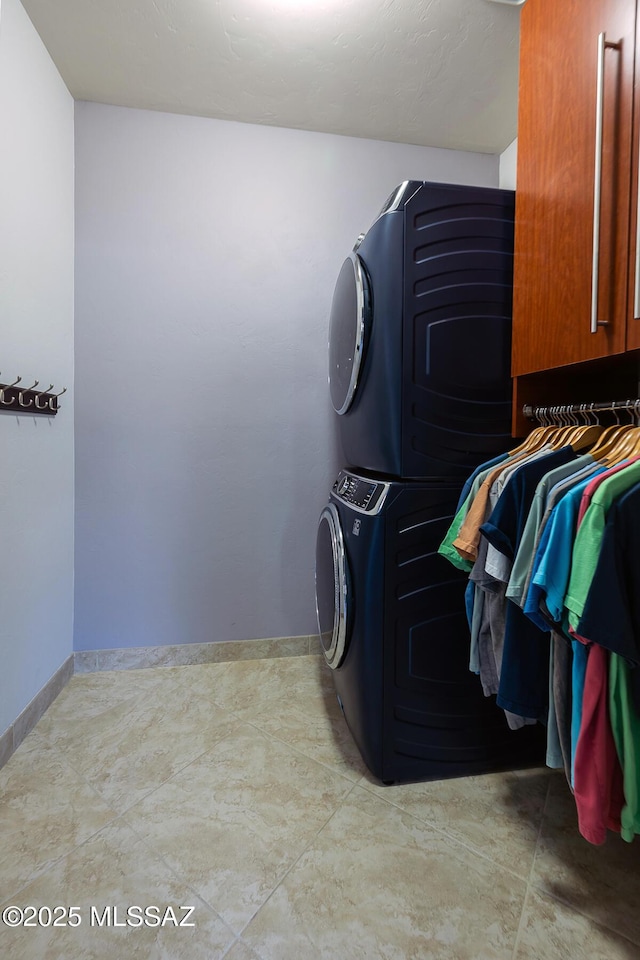 laundry room with baseboards, cabinet space, and stacked washing maching and dryer