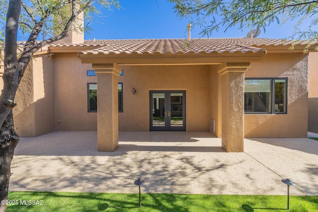 back of property featuring a patio area, a tile roof, stucco siding, and french doors