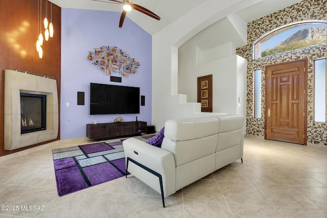 living area featuring high vaulted ceiling, a fireplace, ceiling fan, and light tile patterned floors