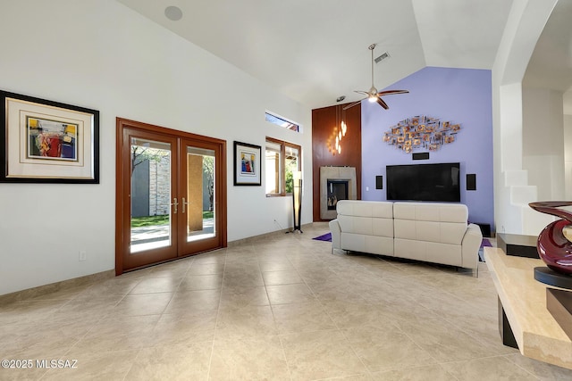 living area with french doors, a fireplace, visible vents, a ceiling fan, and high vaulted ceiling