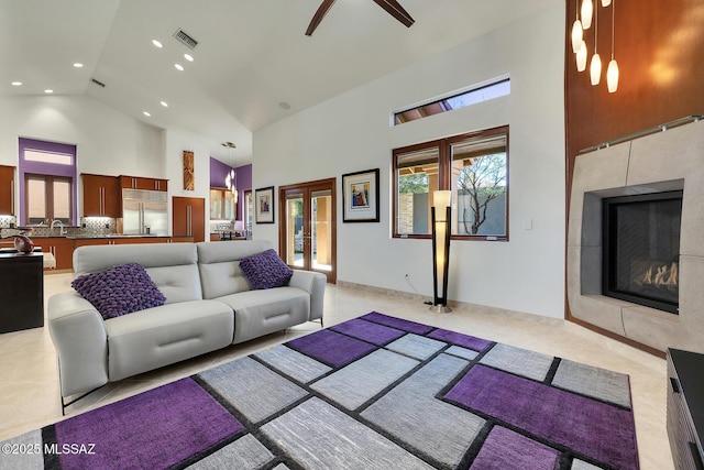 living area with high vaulted ceiling, a tile fireplace, recessed lighting, visible vents, and french doors