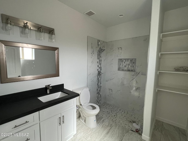 bathroom with vanity, toilet, and tiled shower