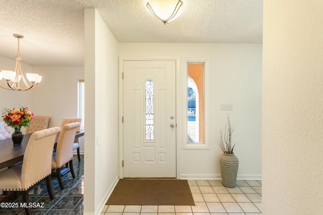 tiled entrance foyer featuring a textured ceiling and an inviting chandelier