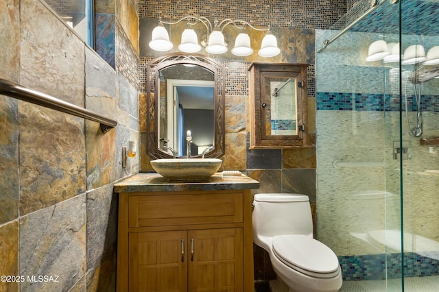 bathroom with vanity, a shower with shower door, tile walls, and toilet