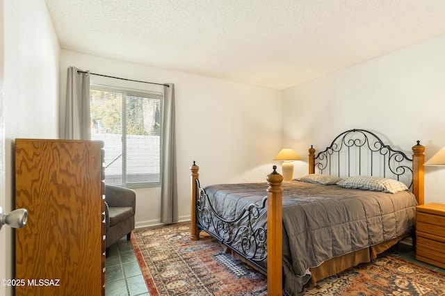 bedroom with dark tile patterned flooring and a textured ceiling