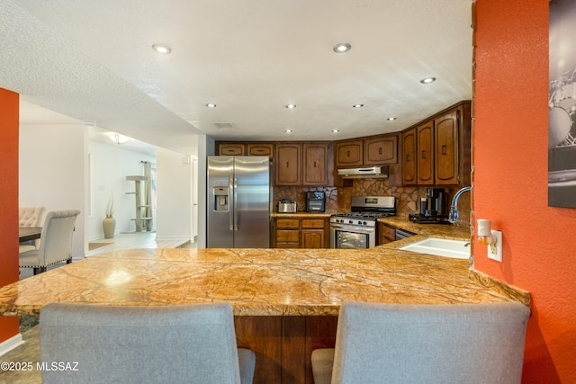 kitchen featuring tasteful backsplash, sink, stainless steel appliances, and kitchen peninsula