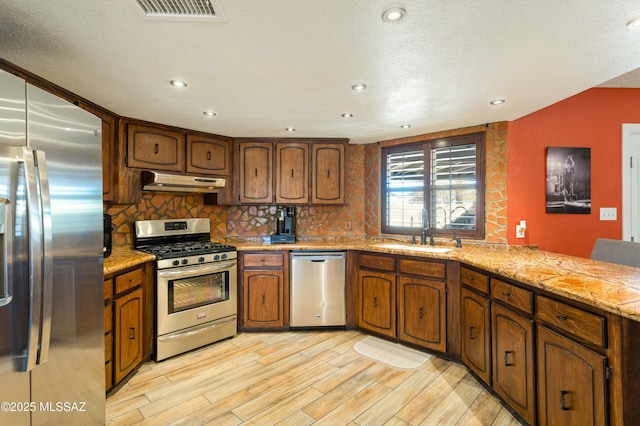 kitchen featuring sink, backsplash, light hardwood / wood-style floors, and appliances with stainless steel finishes