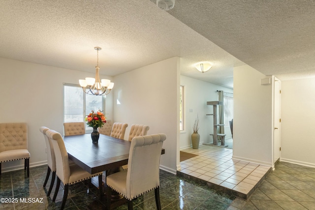 dining space featuring a chandelier, a textured ceiling, and dark tile patterned floors