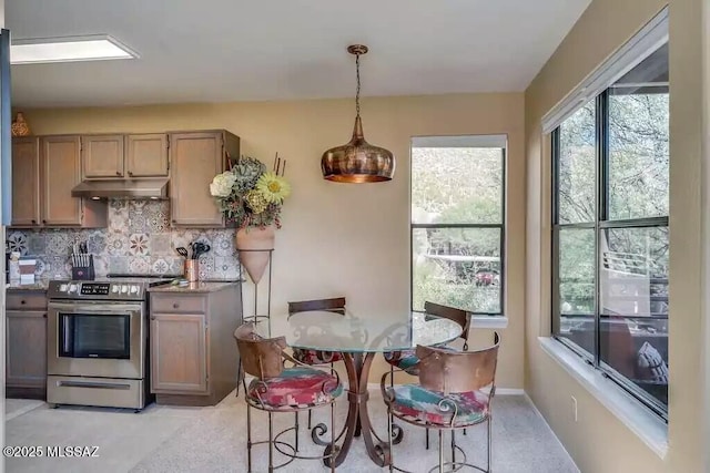 kitchen with pendant lighting, light stone counters, decorative backsplash, and stainless steel range with electric cooktop