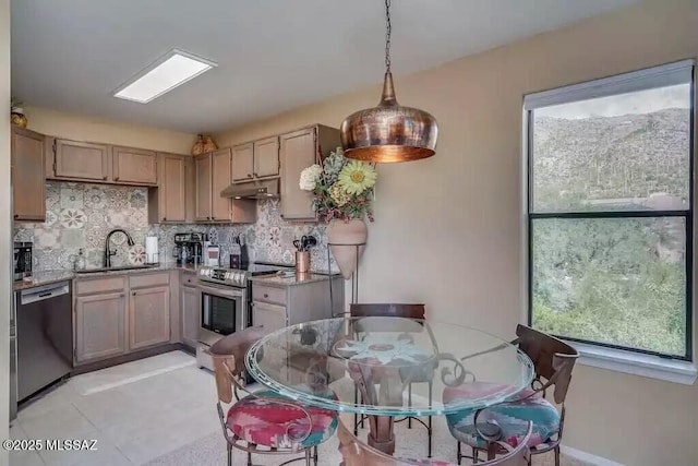 kitchen with pendant lighting, stainless steel appliances, light stone countertops, and sink