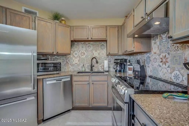kitchen with appliances with stainless steel finishes, tasteful backsplash, sink, light stone counters, and light brown cabinets